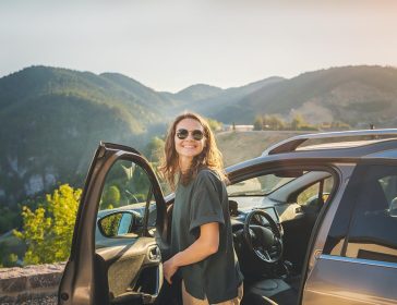 Young beautiful woman traveling by car in the mountains, summer vacation and adventure