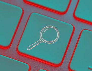 Magnifying glass icon on computer keyboard with neon light